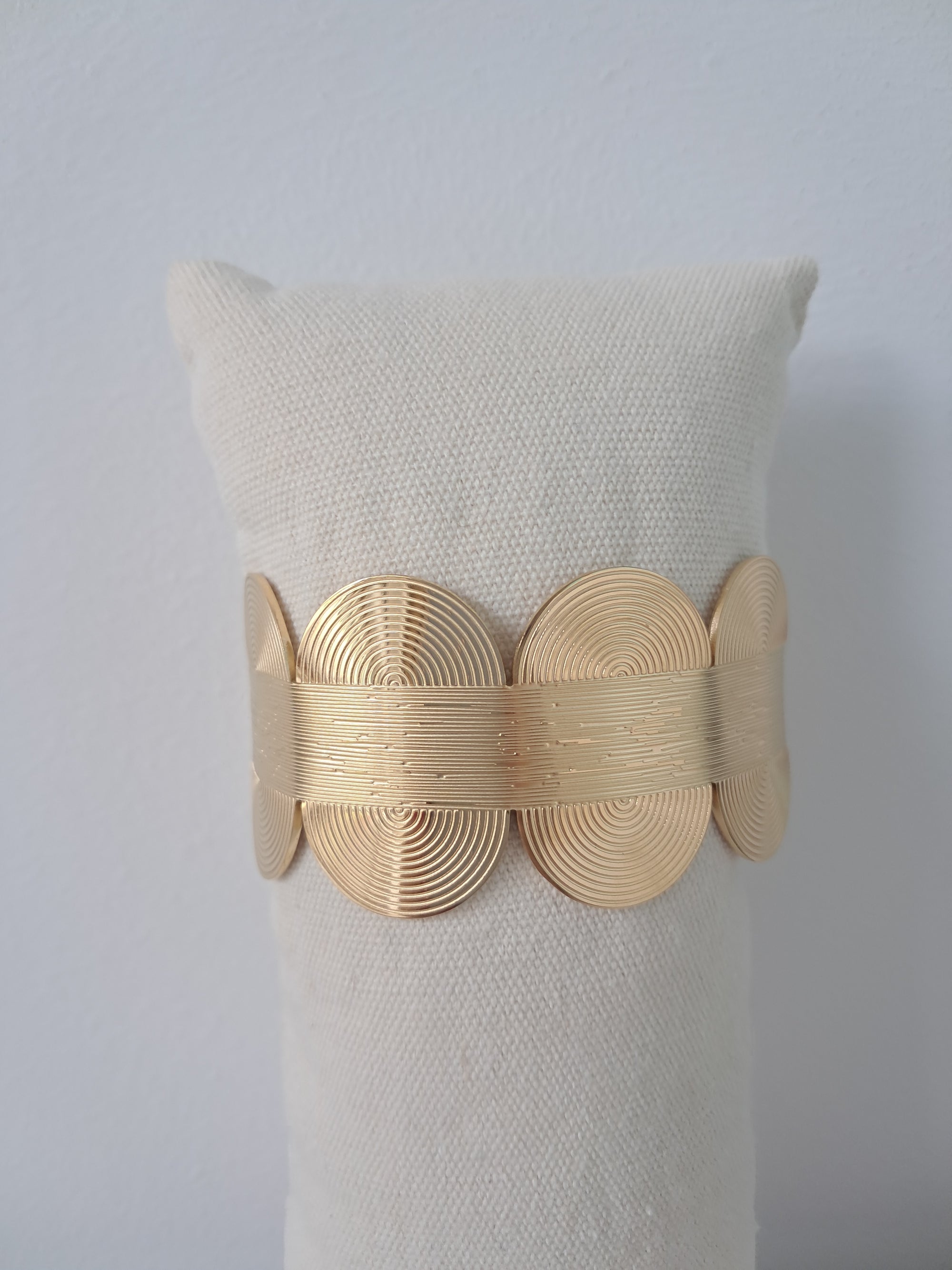 Pulsera dorada rígida con diseño geométrico en relieve